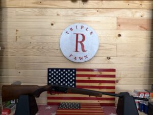 Shotgun displayed with American flags and pawn shop sign