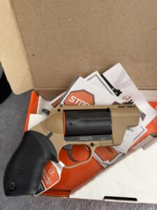 Tan revolver handgun in open box with manuals