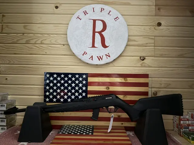 Black rifle displayed before American flag and pawn shop sign