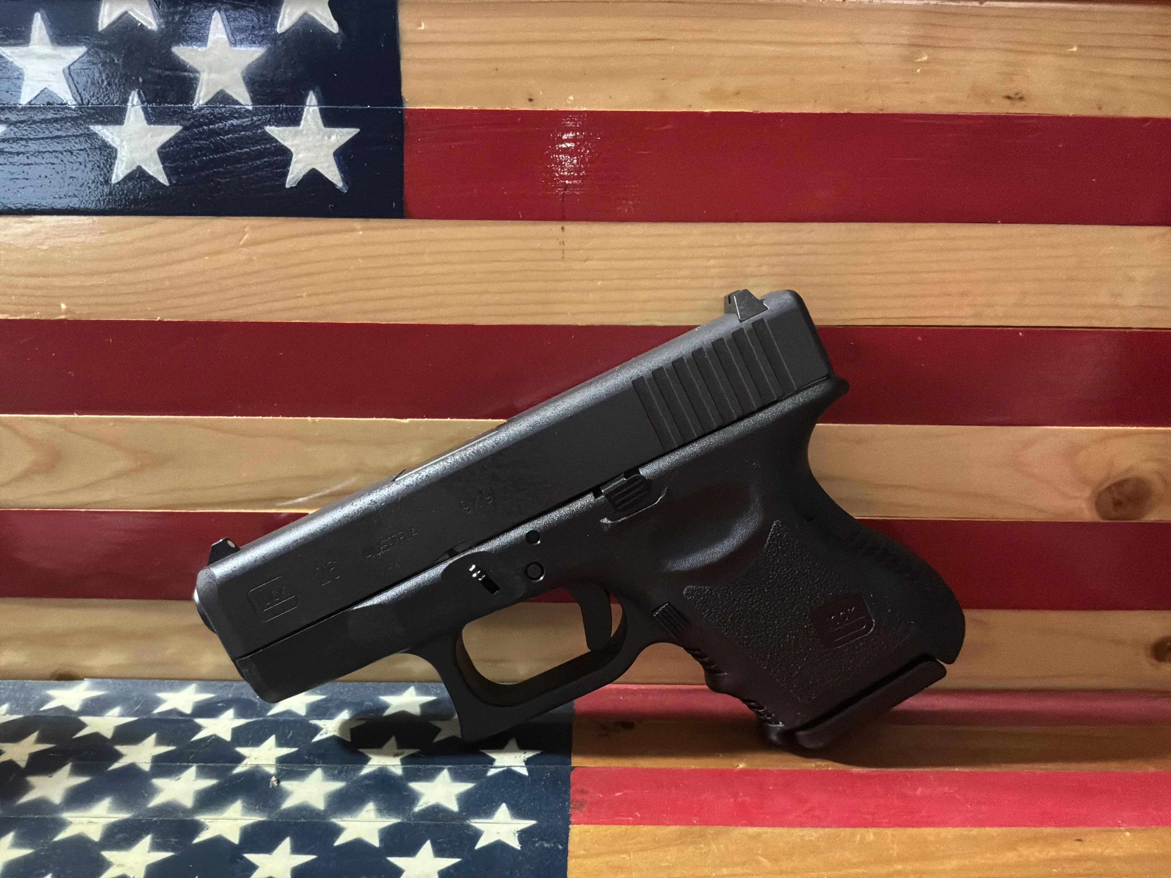 Black semi-automatic handgun displayed before an American flag