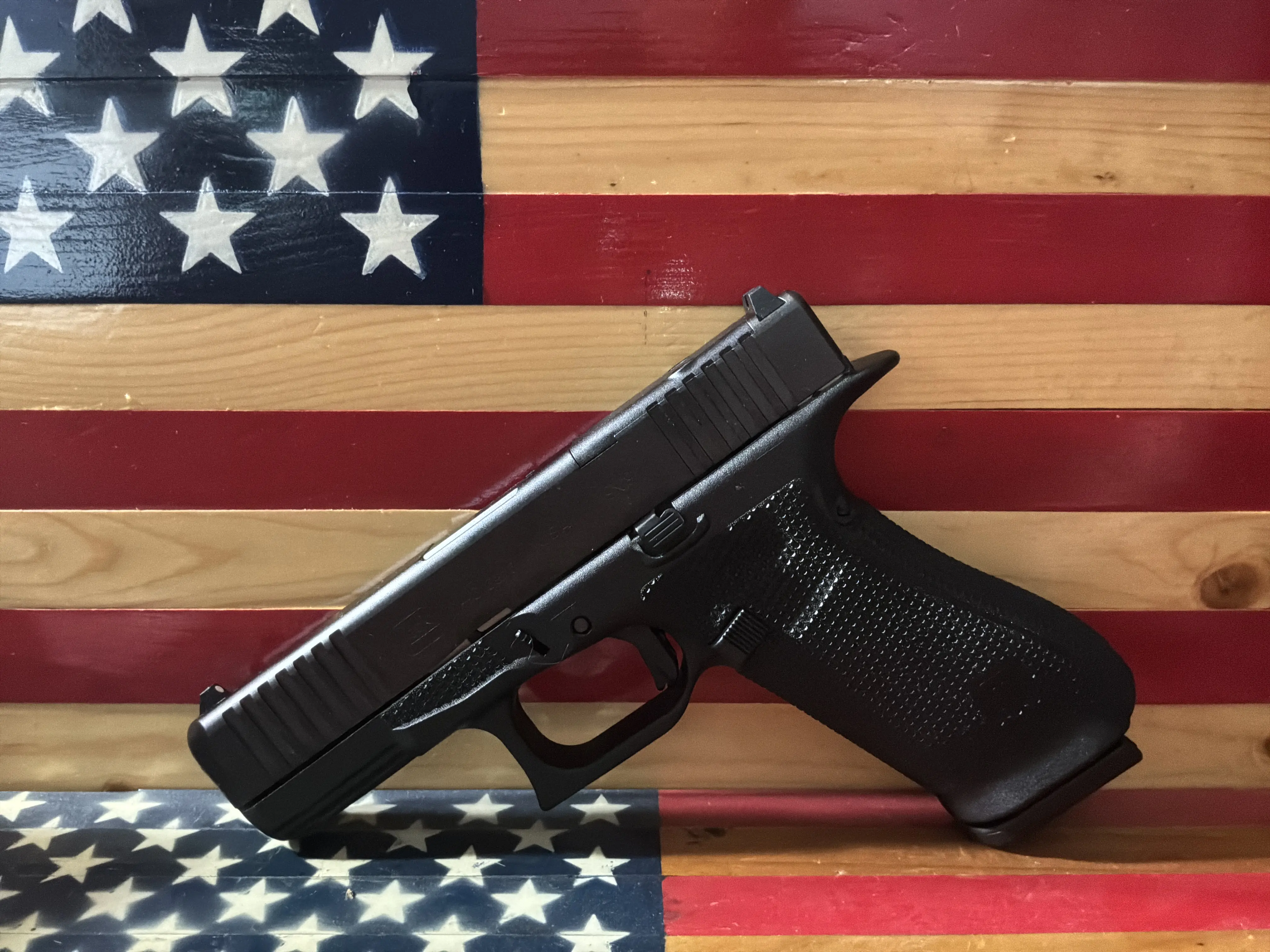 Black semi-automatic pistol on American flag painted wood